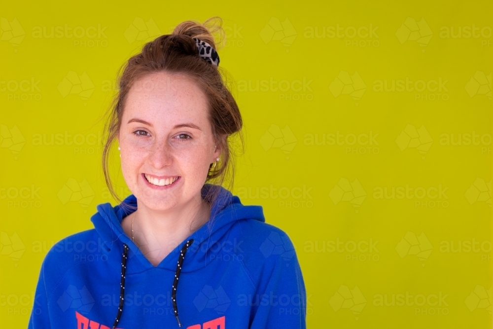 Image of head and shoulders of teenage girl in blue hoody against plain ...