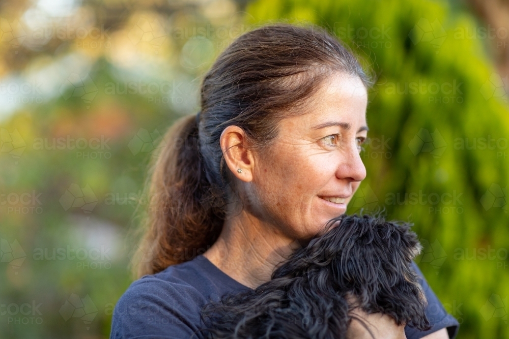 head and shoulders of woman holding small dog - Australian Stock Image