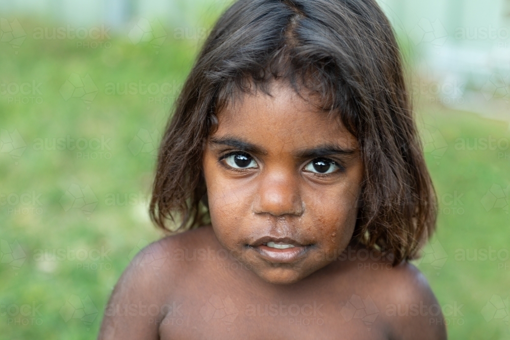 head and shoulders of young child looking up at the camera - Australian Stock Image