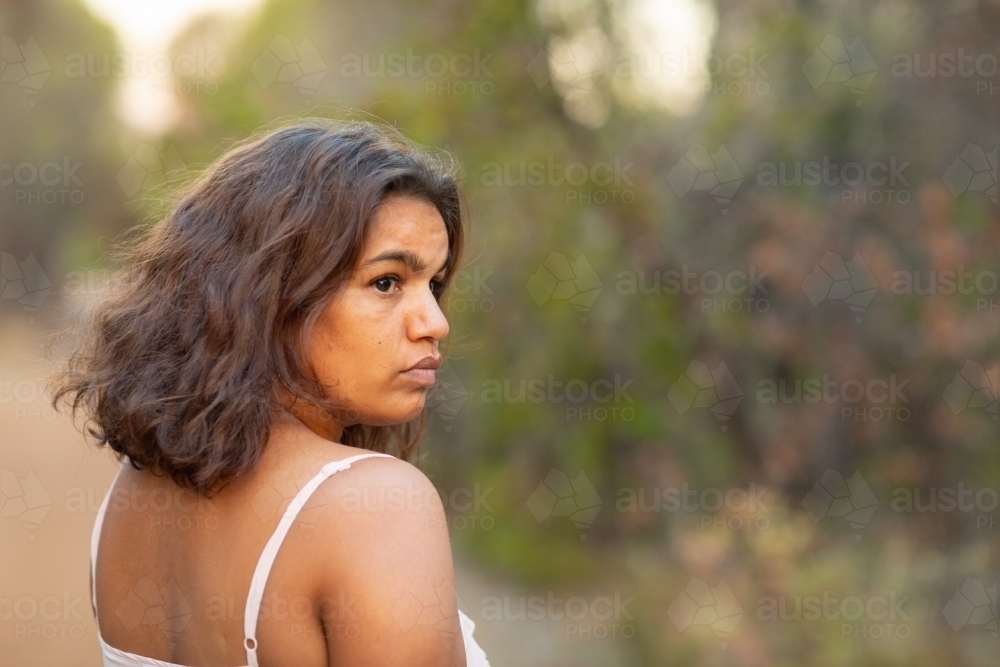head and shoulders of young lady turning to look back over shoulder - Australian Stock Image