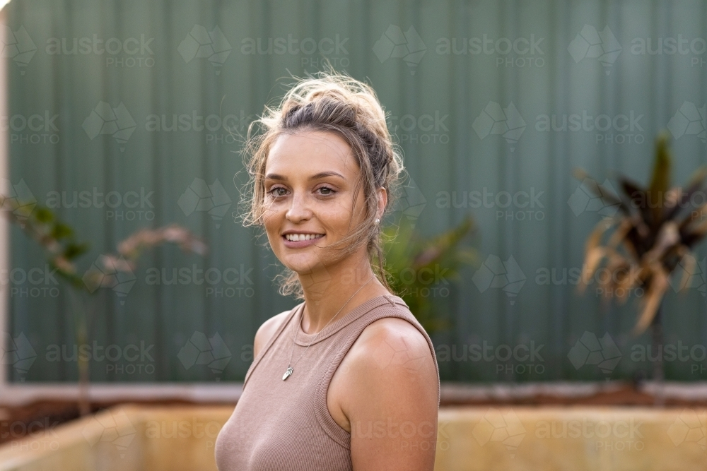 head and shoulders of young lady with hair in messy bun - Australian Stock Image