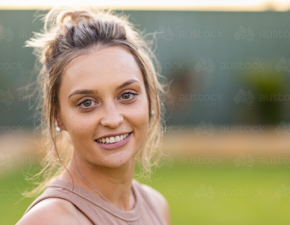 head and shoulders of young lady with hair in messy bun looking at camera - Australian Stock Image