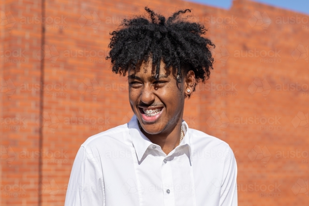 head and shoulders of young man in front of red brick wall - Australian Stock Image