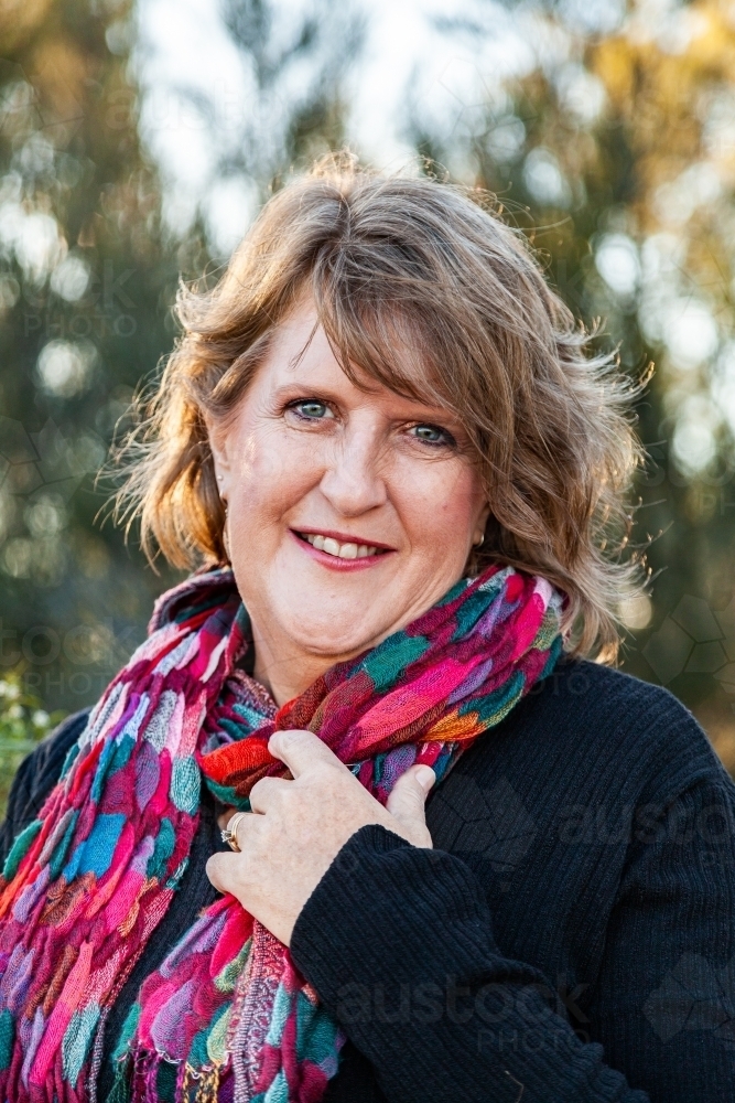 Head and shoulders portrait of a happy middle aged woman with colourful scarf - Australian Stock Image