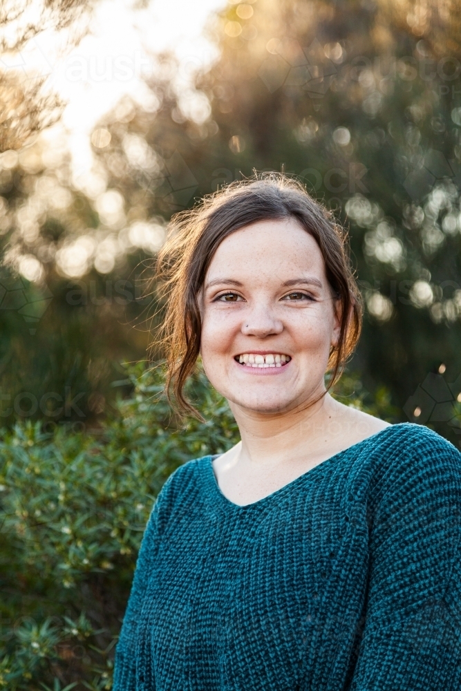 Head and shoulders portrait of a happy young woman with green background - Australian Stock Image