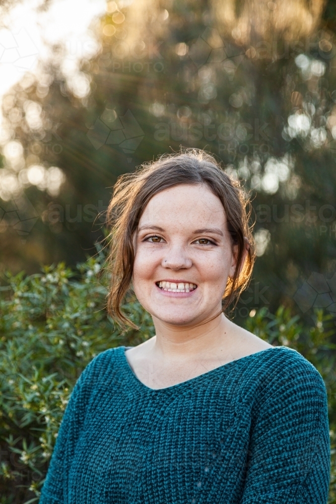 Head and shoulders portrait of a happy young woman with green background - Australian Stock Image