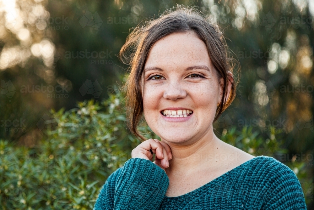 Head and shoulders portrait of a happy young woman with green background - Australian Stock Image