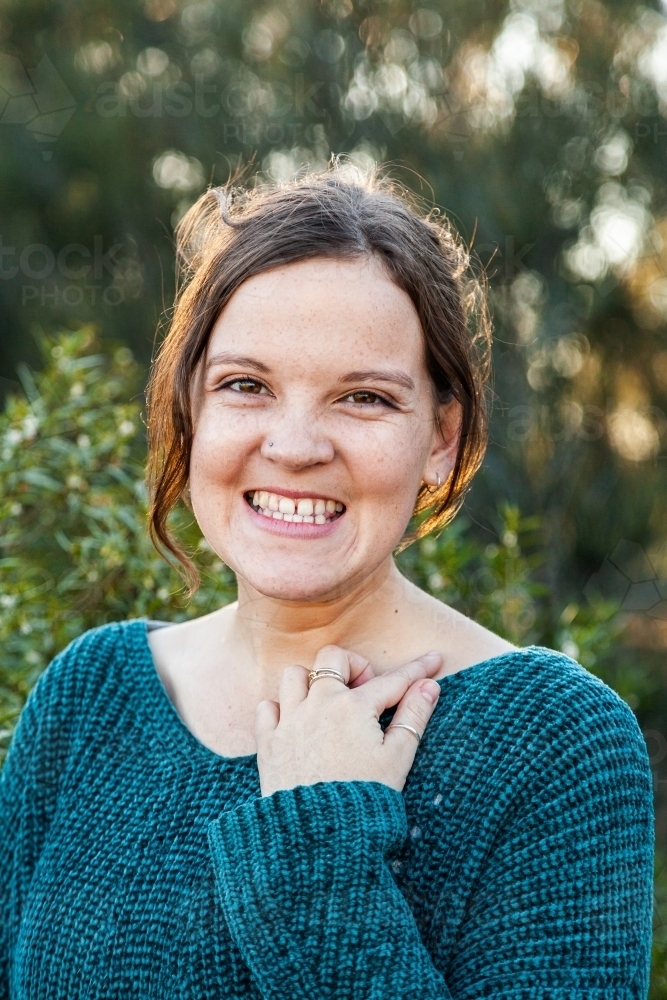 Head and shoulders portrait of a happy young woman with green background - Australian Stock Image
