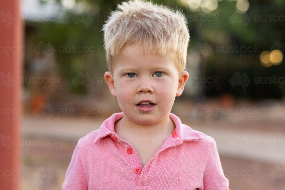 head and shoulders view of little blonde boy in pink shirt - Australian Stock Image
