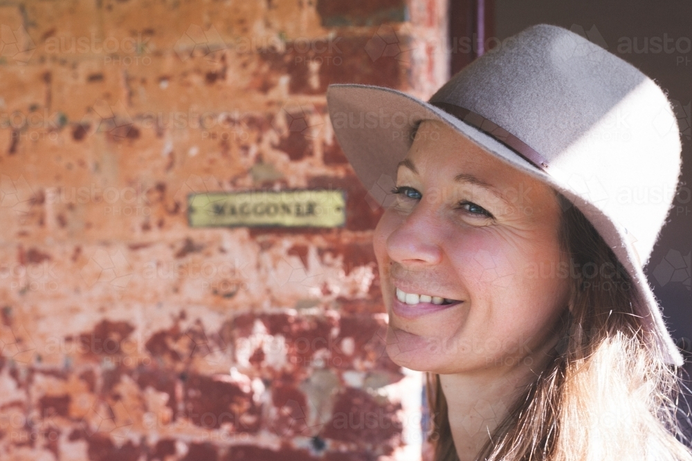 Head of woman smiling in front of rustic wall - Australian Stock Image