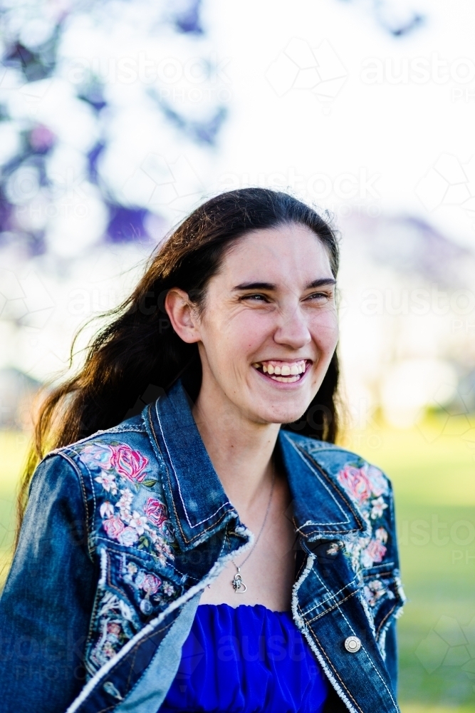 Head shot portrait of happy woman laughing outside - Australian Stock Image