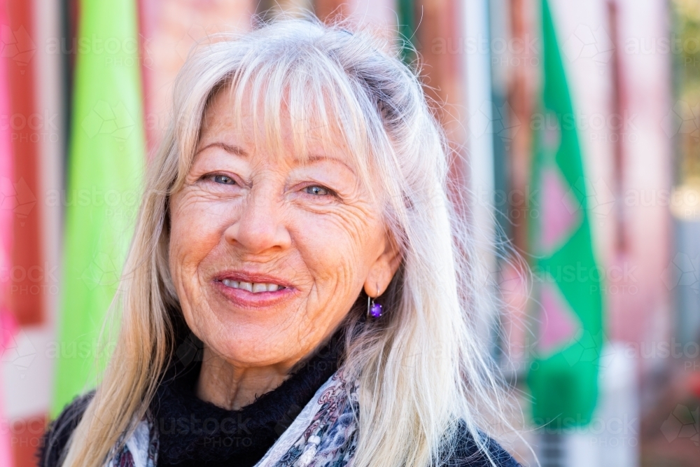 Headshot of mature woman with fair hair wearing scarf smiling - Australian Stock Image