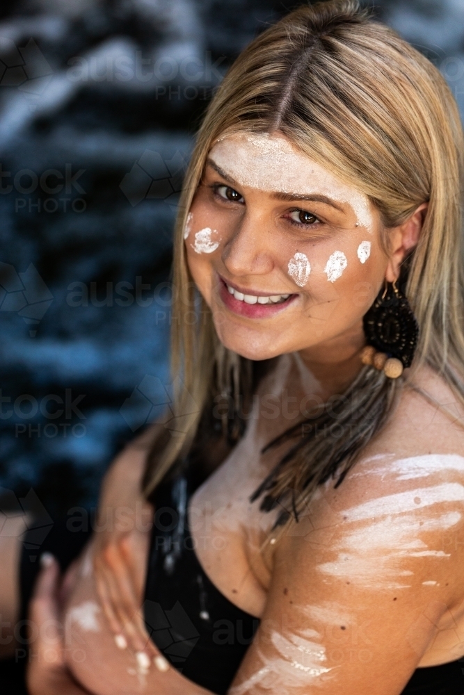 Headshot portrait of smiling First Nations Australian woman with flowing water backdrop - Australian Stock Image