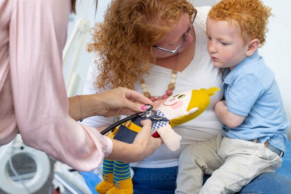 health professional demonstrating stethoscope on toy for little boy - Australian Stock Image