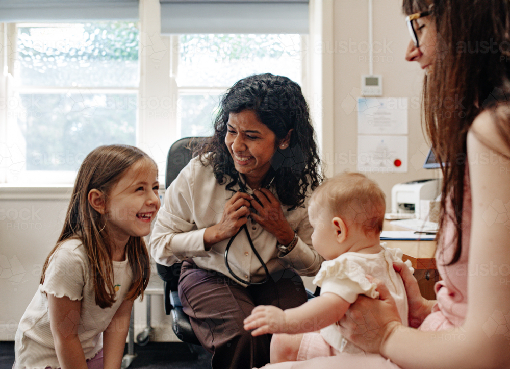 Healthcare professional meets with a parent and her kids during a clinic consultation - Australian Stock Image