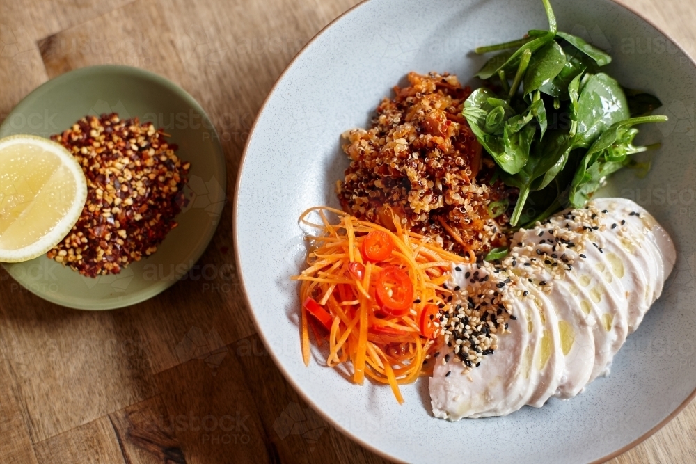 Healthy chicken and salad dish on wooden table in cafe - Australian Stock Image