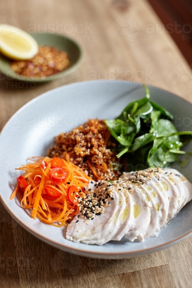 Healthy chicken and salad dish on wooden table in cafe - Australian Stock Image