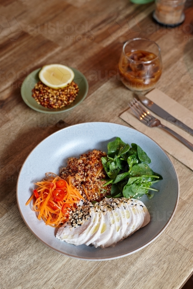 Healthy chicken and salad dish on wooden table in cafe - Australian Stock Image