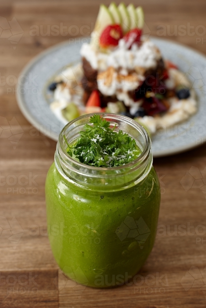 Healthy organic green smoothie drink on wooden table - Australian Stock Image
