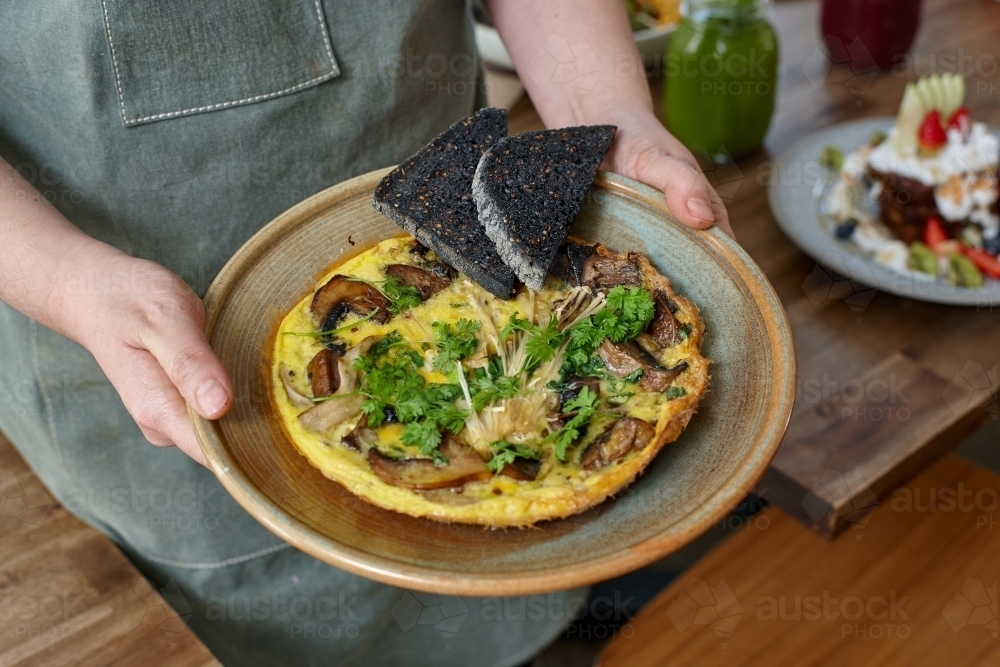 Healthy organic omelet and toast on plate being held by waiter - Australian Stock Image