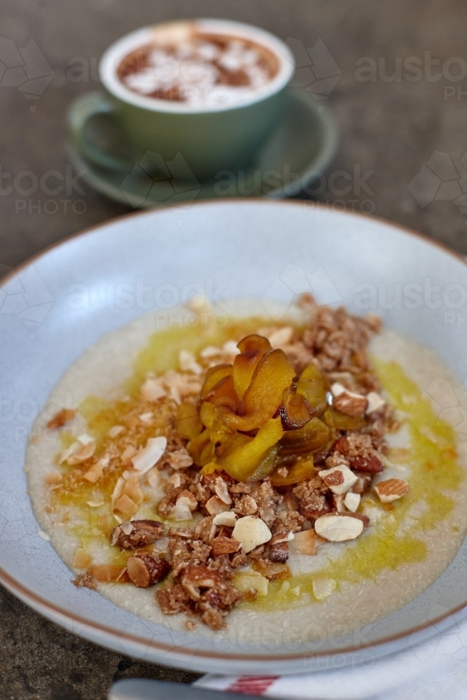 Healthy porridge served with hot beverage in vegetarian cafe - Australian Stock Image