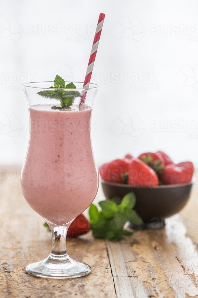 Healthy Strawberry Smoothie with straw and bowl of fresh strawberries - Australian Stock Image