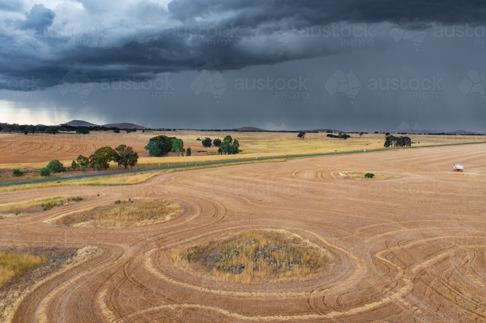 Image of Heavy rain and dark cloud over dry harvested paddocks