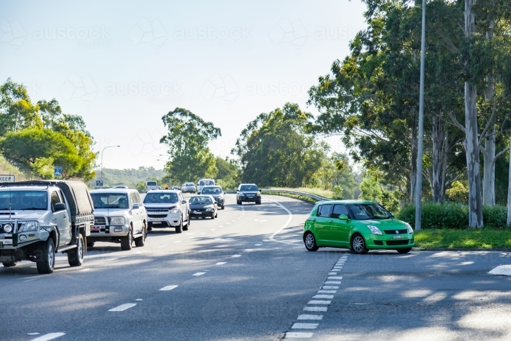Heavy traffic and green car making left hand turn off highway - Australian Stock Image