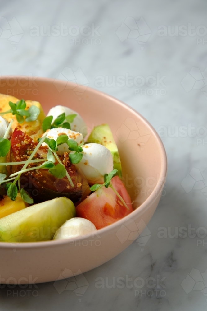 Heirloom tomatoes salad with mozzarella cheese in a pink bowl - Australian Stock Image