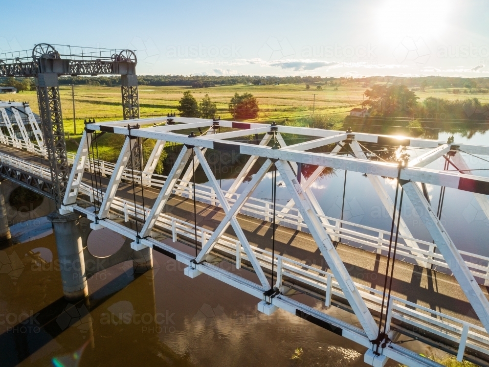 Heritage listed overhead-braced timber truss road bridge over river in sunlight - Australian Stock Image