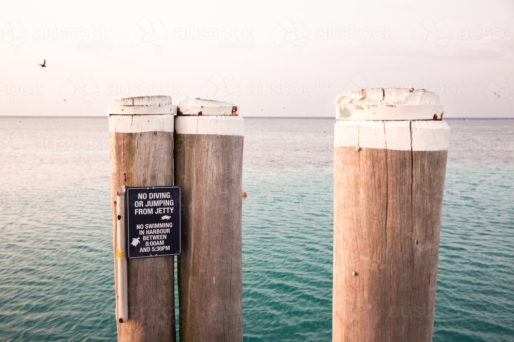 Image of Heron Island Jetty posts and warning sign - Austockphoto