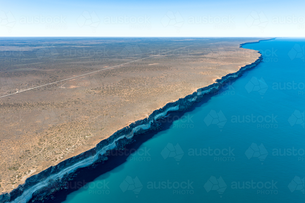 High aerial view of a straight road following the edge of steep limestone cliffs by the ocean - Australian Stock Image