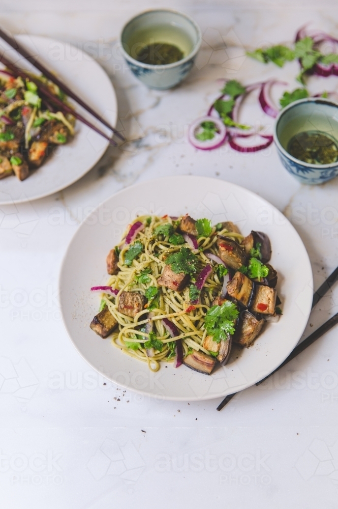 High angle of cold soba noodle and eggplant salad with green tea on white marble background - Australian Stock Image