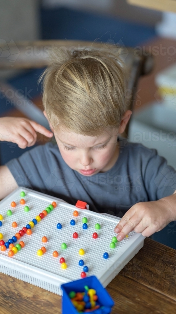 High angle shot of child doing a puzzle - Australian Stock Image