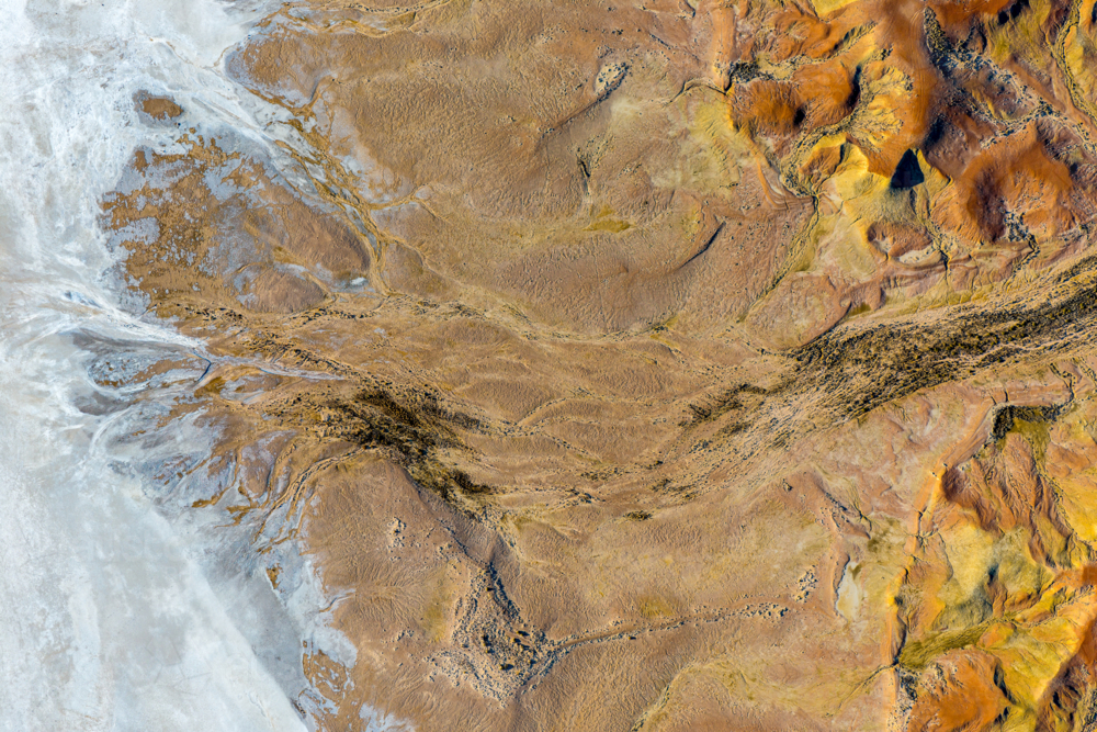 High-angle view of textured salt flats meeting golden sand dunes and dark drainage patterns - Australian Stock Image