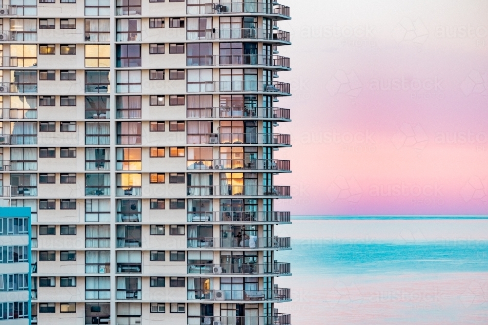 Image of High rise seaside apartment building with pink sunset over the ...