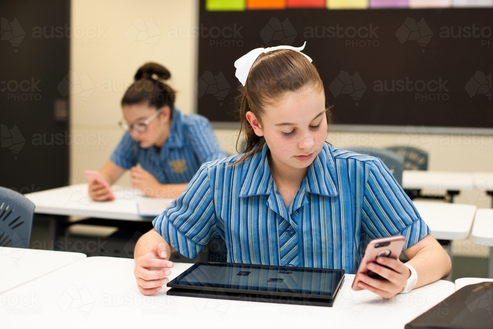 High school student looking at her phone in the classroom - Australian Stock Image