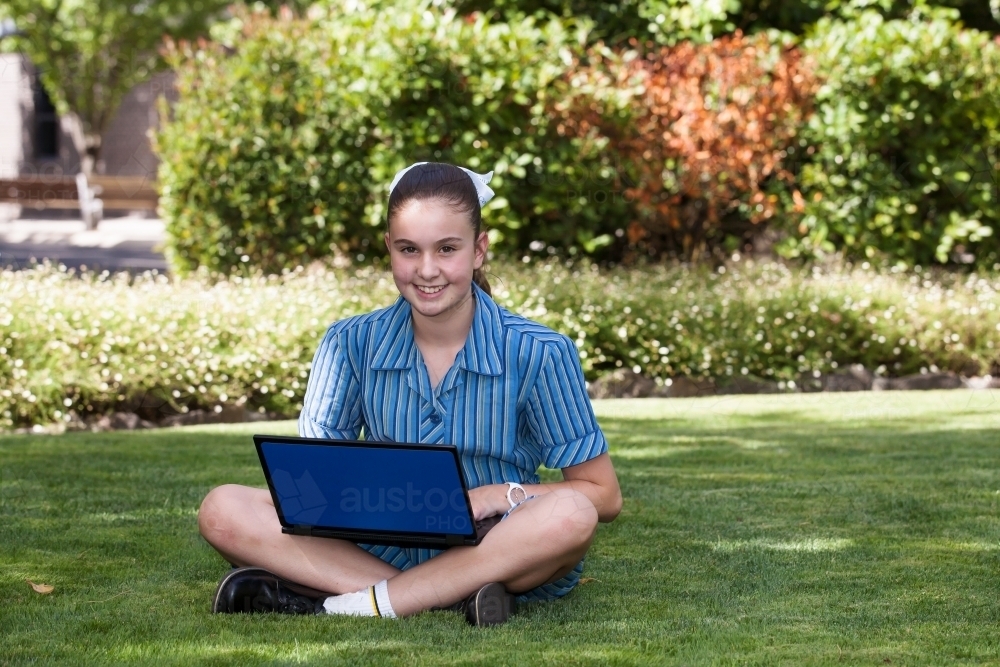High school student working on laptop in the gardens - Australian Stock Image