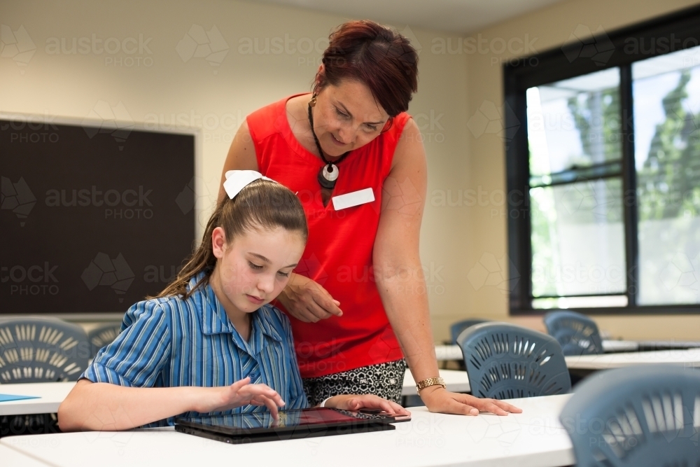 High school teacher helping a student in a classroom - Australian Stock Image
