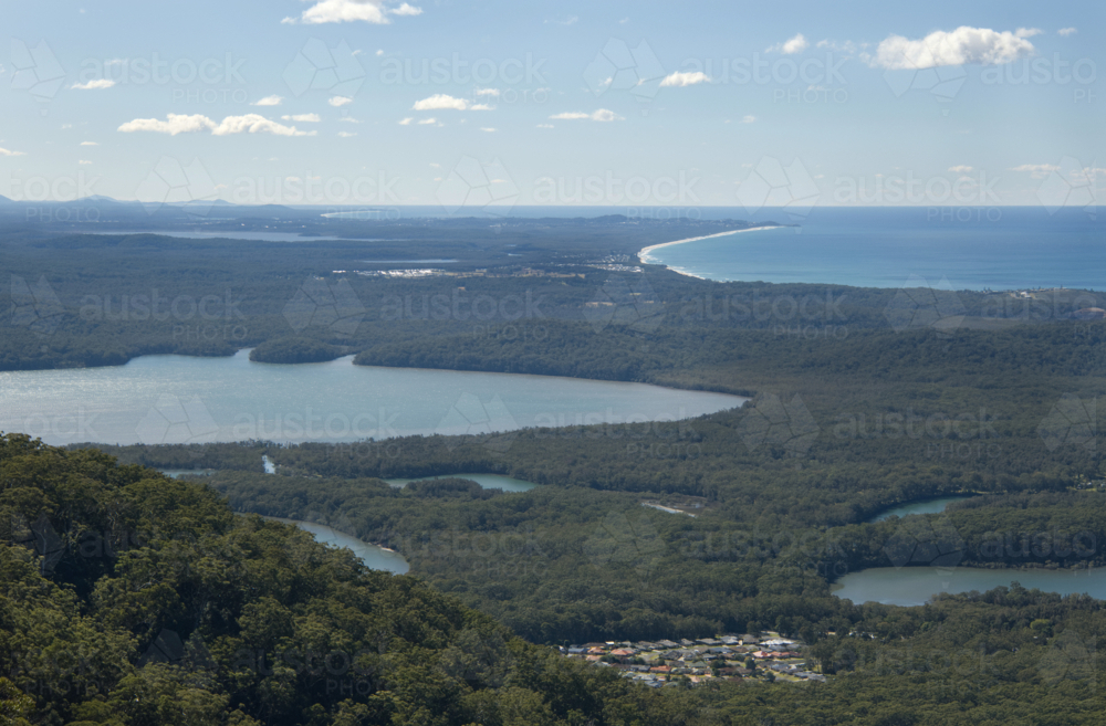 High view of a lake next to beaches and bush with a small village - Australian Stock Image
