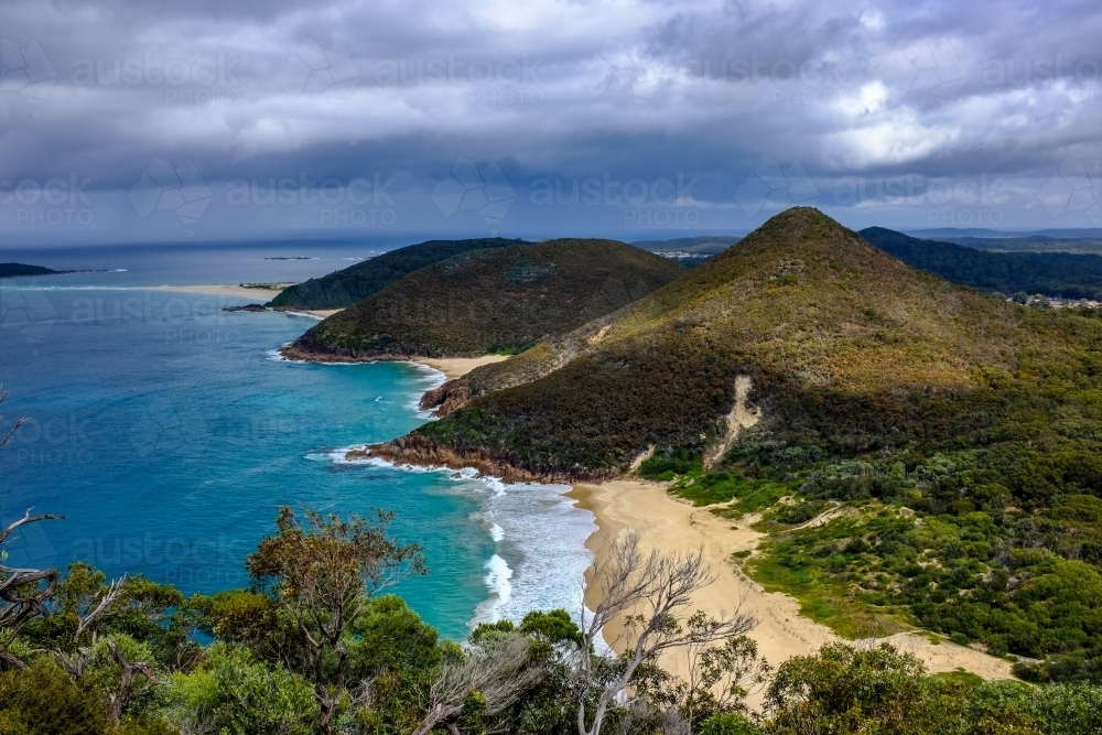 High view of beach and mountain with moody sky - Australian Stock Image