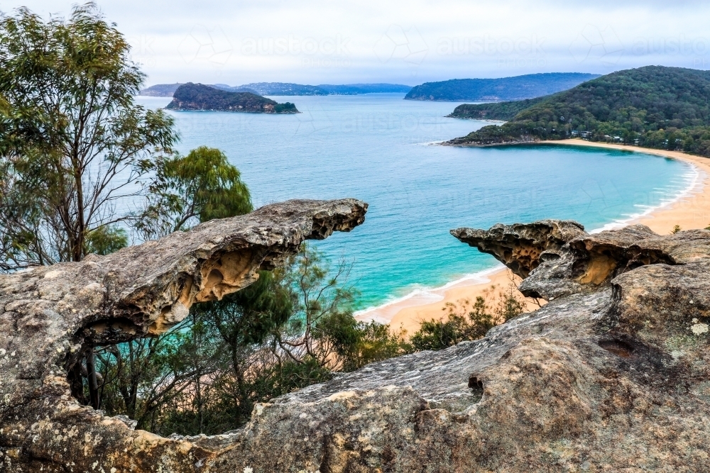 High view of ocean and beach through rocky outcrop - Australian Stock Image