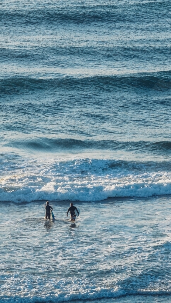 High view of two surfers entering beach - Australian Stock Image