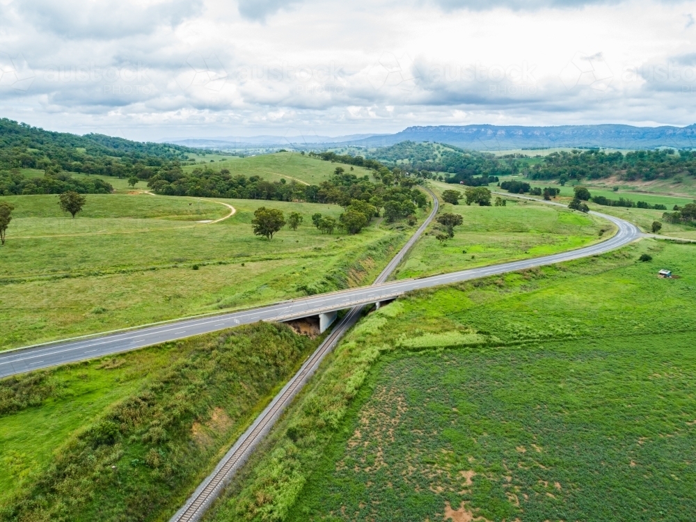 Highway road with bridge going over train line in green countryside - Australian Stock Image