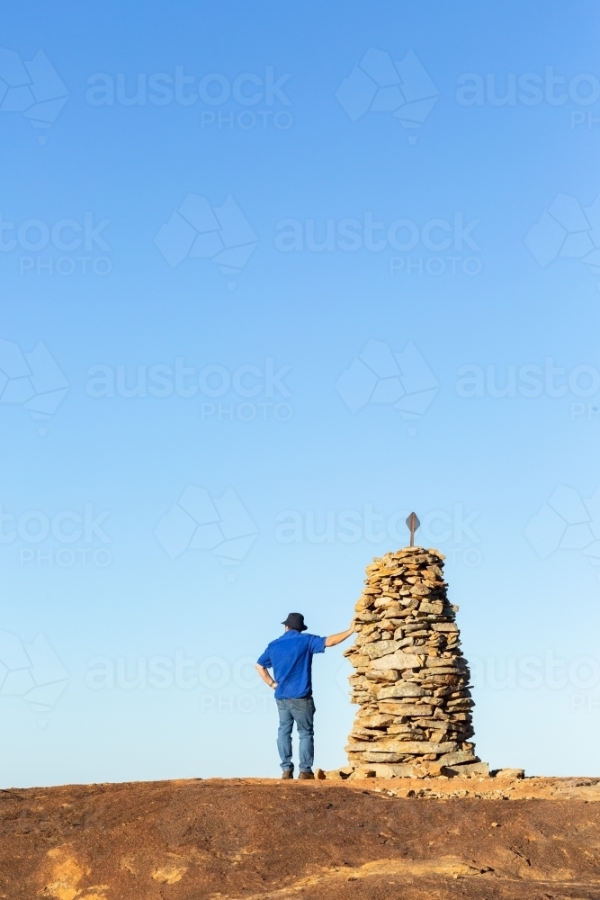 Hiker atop granite outcrop next to rock cairn - Australian Stock Image