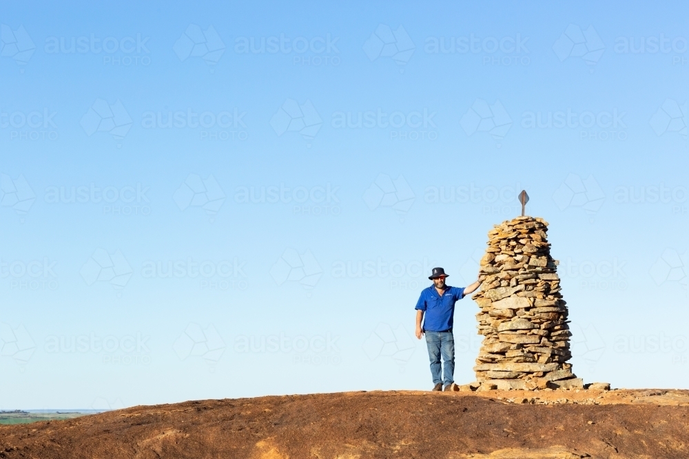 Hiker atop granite outcrop next to rock cairn - Australian Stock Image