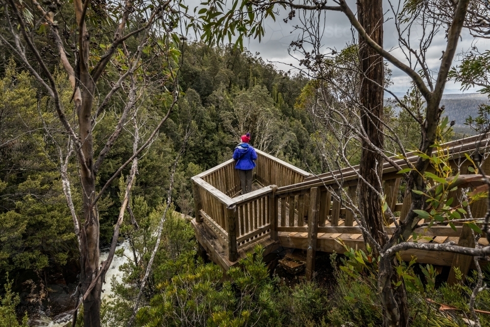 hiker gazing across wilderness scene from a lookout - Australian Stock Image