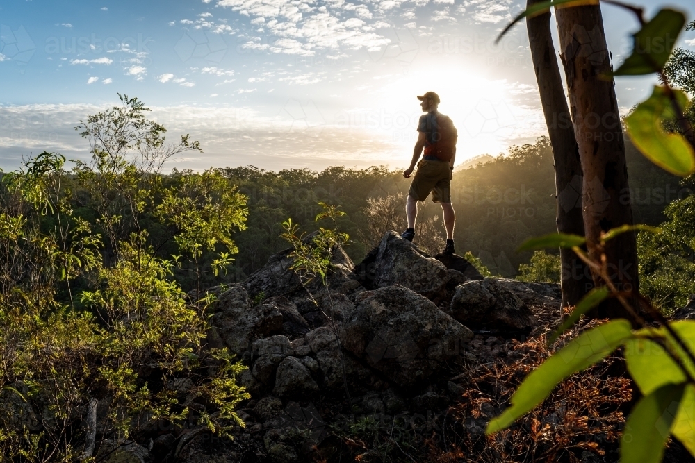 hiker stands overlooking a wilderness scene - Australian Stock Image