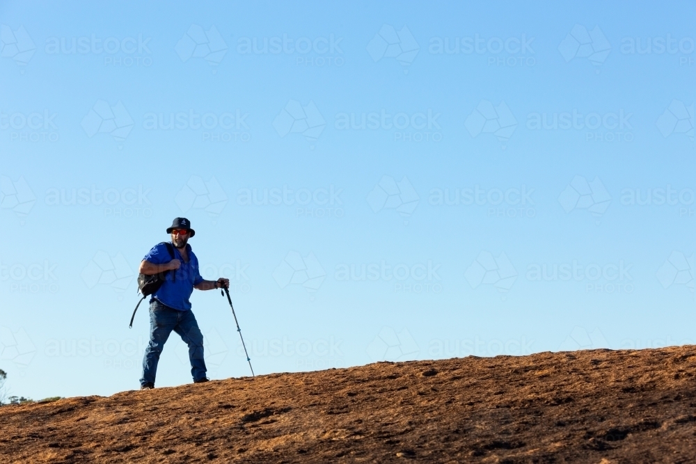 hiker walking along path on granite rock - Australian Stock Image