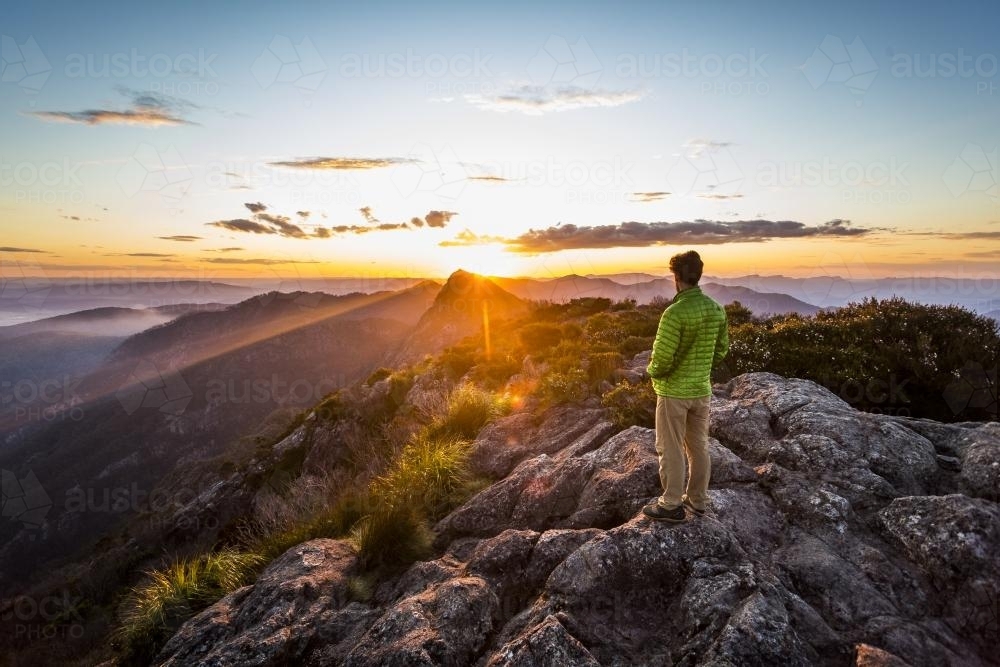 Hiker watching mountain sunset from the east peak of Mount Barney - Australian Stock Image
